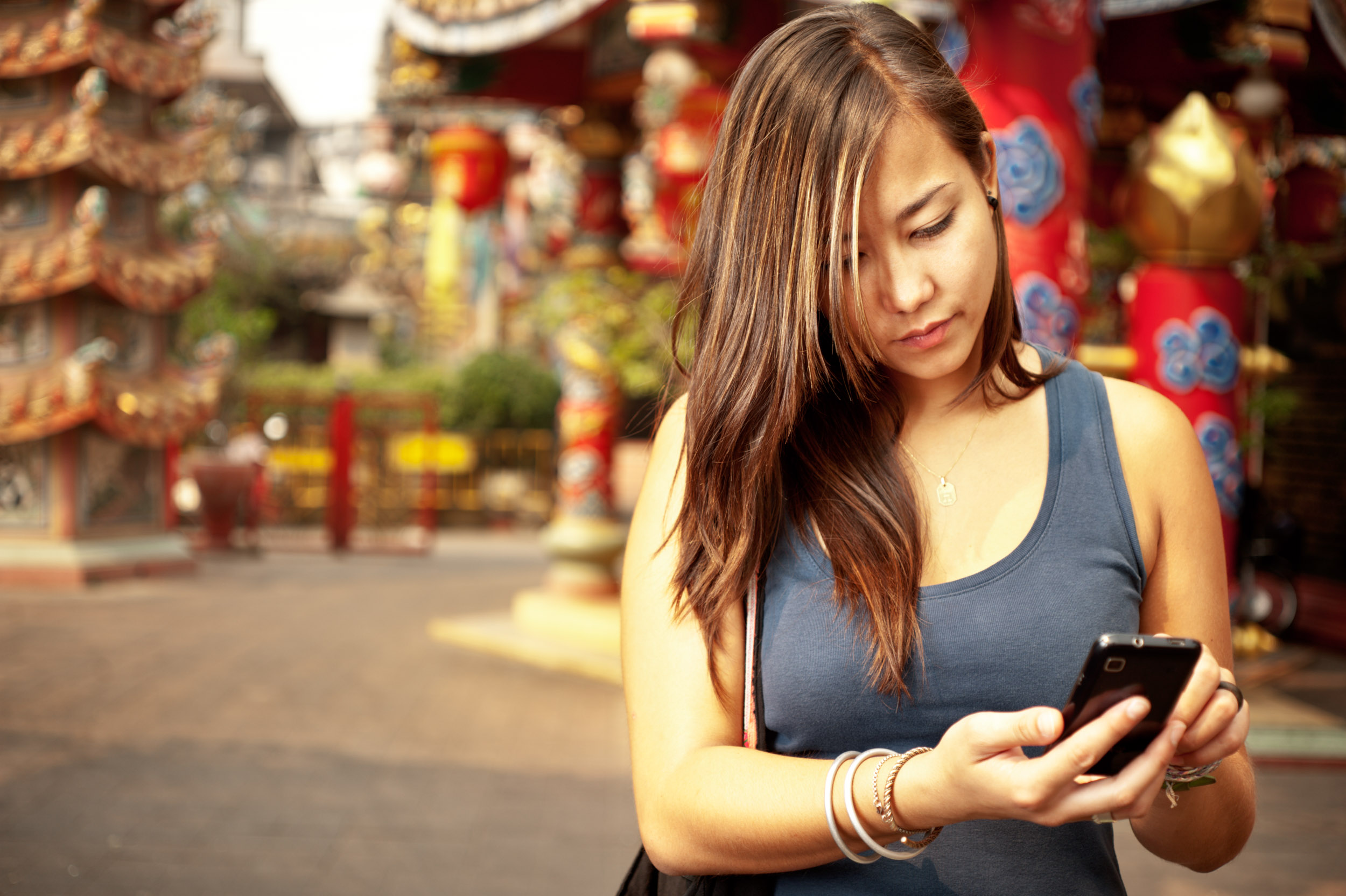 Femme touchant son smartphone avec un doigt avec des bâtiments aux couleurs vives en arrière-plan